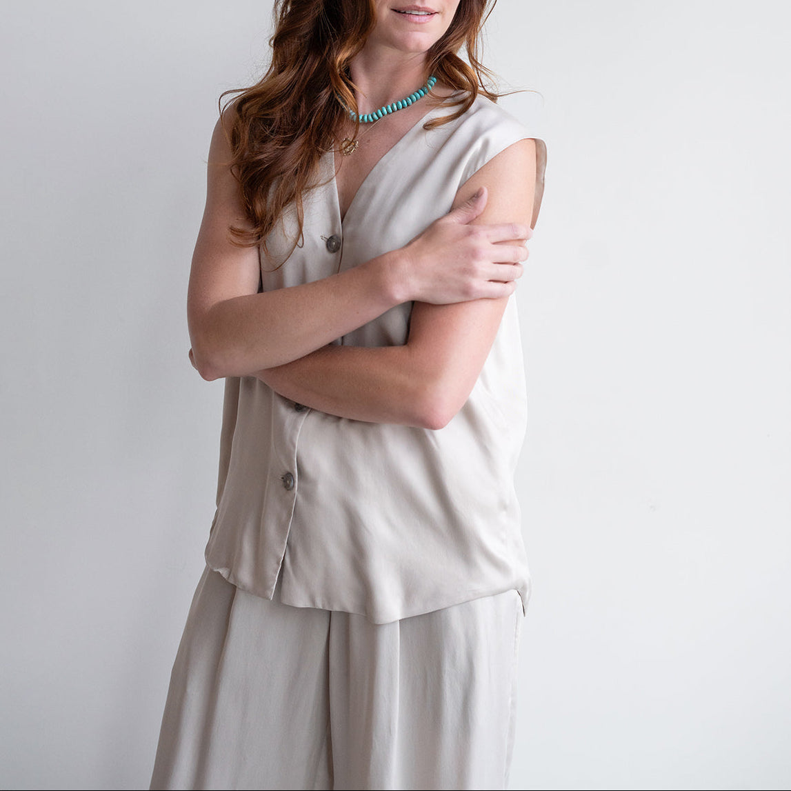 Model wearing a sanded vest in sisal with V-neckline and front buttons, showcasing an unlined, sustainable design.