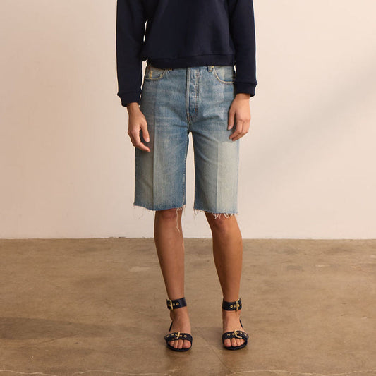 Cut knee shorts in worn indigo, mid-rise fit, 100% cotton, styled with a dark sweater and sandals.