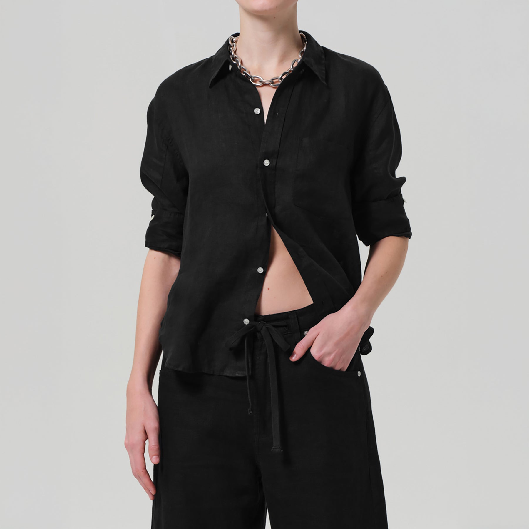 Stylish model wearing the Kayla Shrunken Shirt in Black, featuring a tailored fit and high-low hem, made from 100% linen.