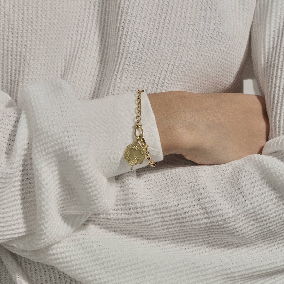 Taurus Pendant in 9K Yellow Gold showcased on a wrist with a white sweater.