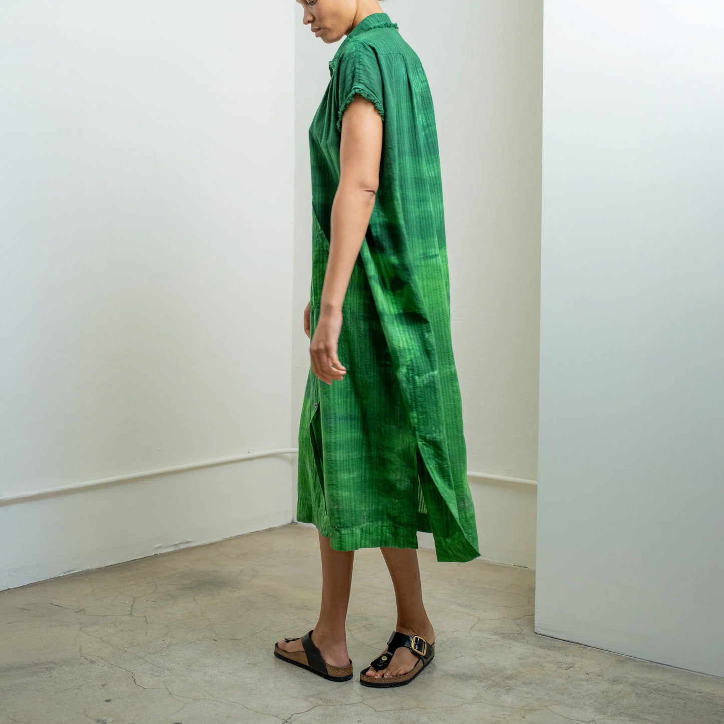 Model wearing a green rainbow caftan dress, showcasing its oversized fit and fringed edges from the back.