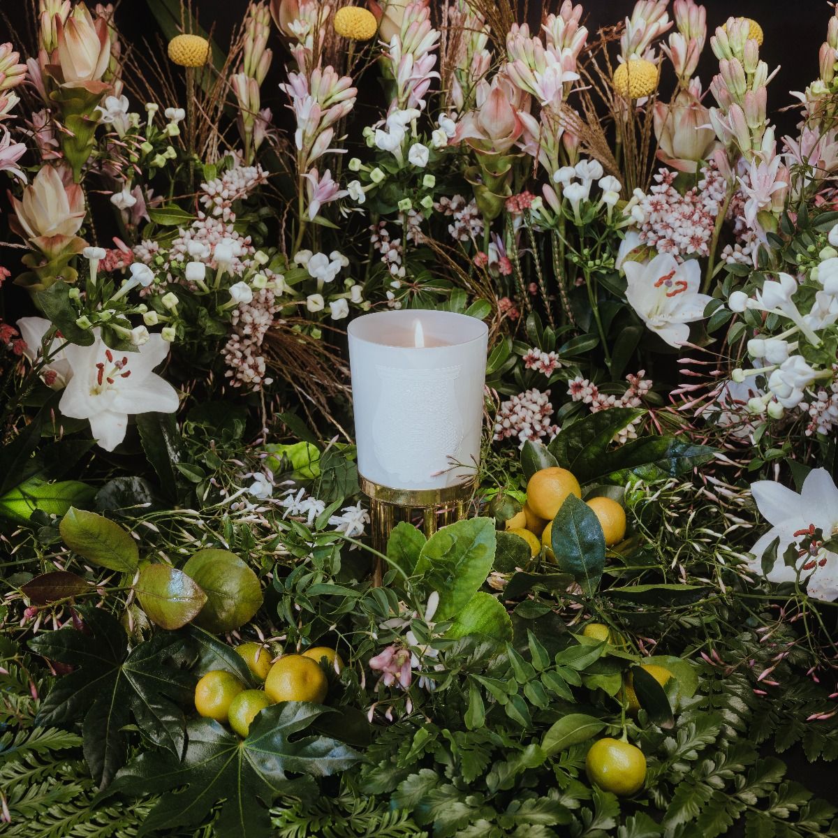 Positano candle by Giambattista Valli surrounded by vibrant floral arrangement and fresh greenery.