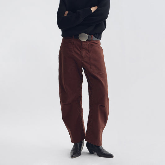Model wearing Tribeca Pant in Cabernet with a relaxed fit, paired with a black sweater and stylish boots.