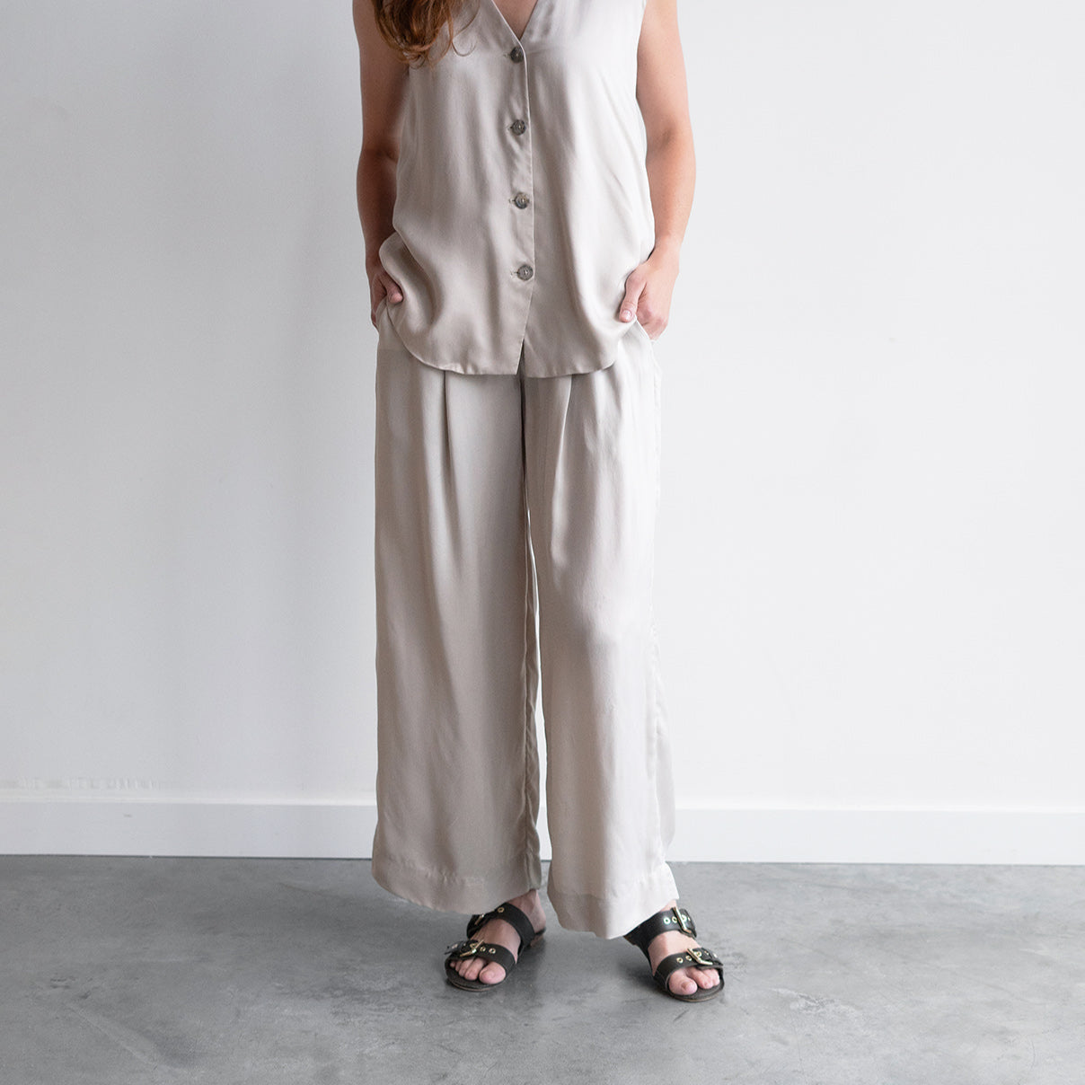 Model wearing sanded trousers in sisal with an elastic waistband and buttons, showcasing sustainable fashion.