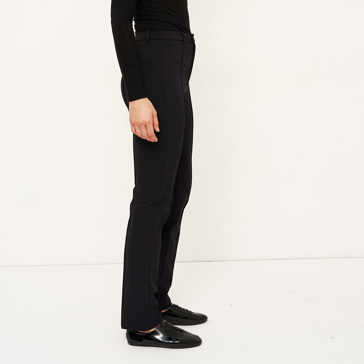 The Riding Pant in Black shown from the side, featuring a slim and tailored fit.