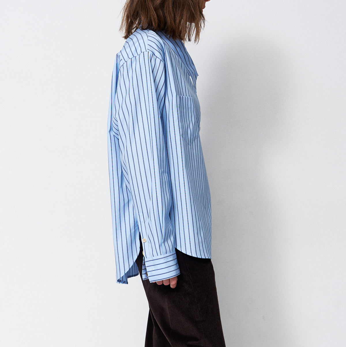 The Asymmetry Shirt in Cornflower Stripe shown from the side, highlighting its button front and asymmetric design.
