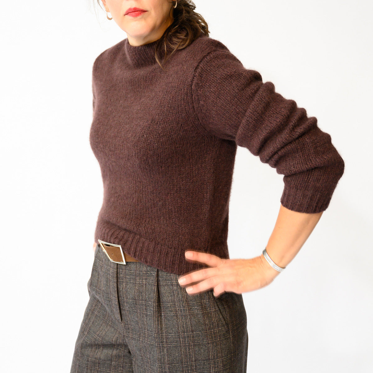 Maire Sweater in Red Umber worn with stylish trousers, features a fitted silhouette with blouson sleeves and ribbed cuffs.