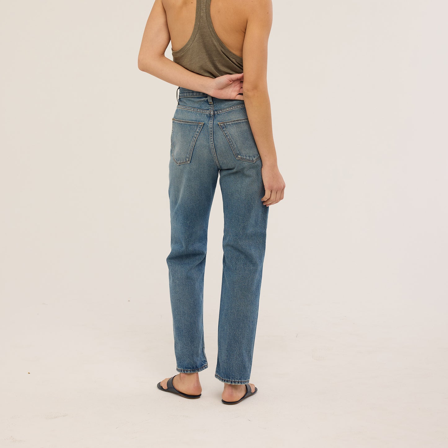 Model wearing Sunday Jean in Borrego Indigo, high-waisted, fitted rigid denim, showcasing back view.