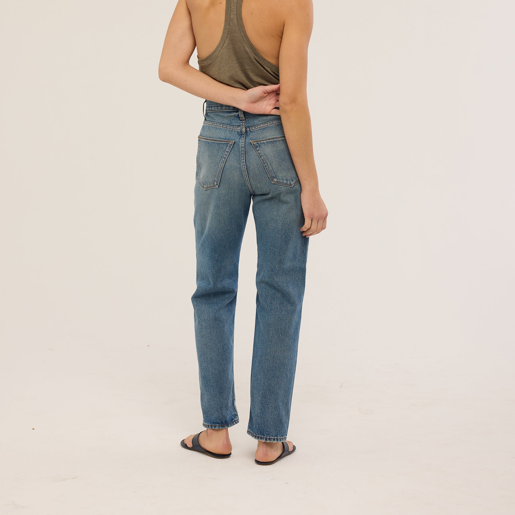 Model wearing Sunday Jean in Borrego Indigo, high-waisted, fitted rigid denim, showcasing back view.