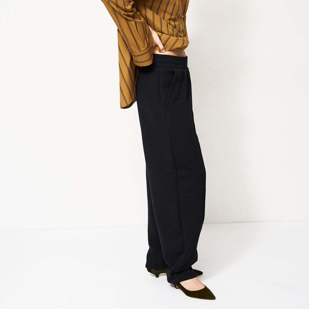 Model wearing Pintuck Track Pant in Black with a relaxed fit and pintucks, styled with a striped top.