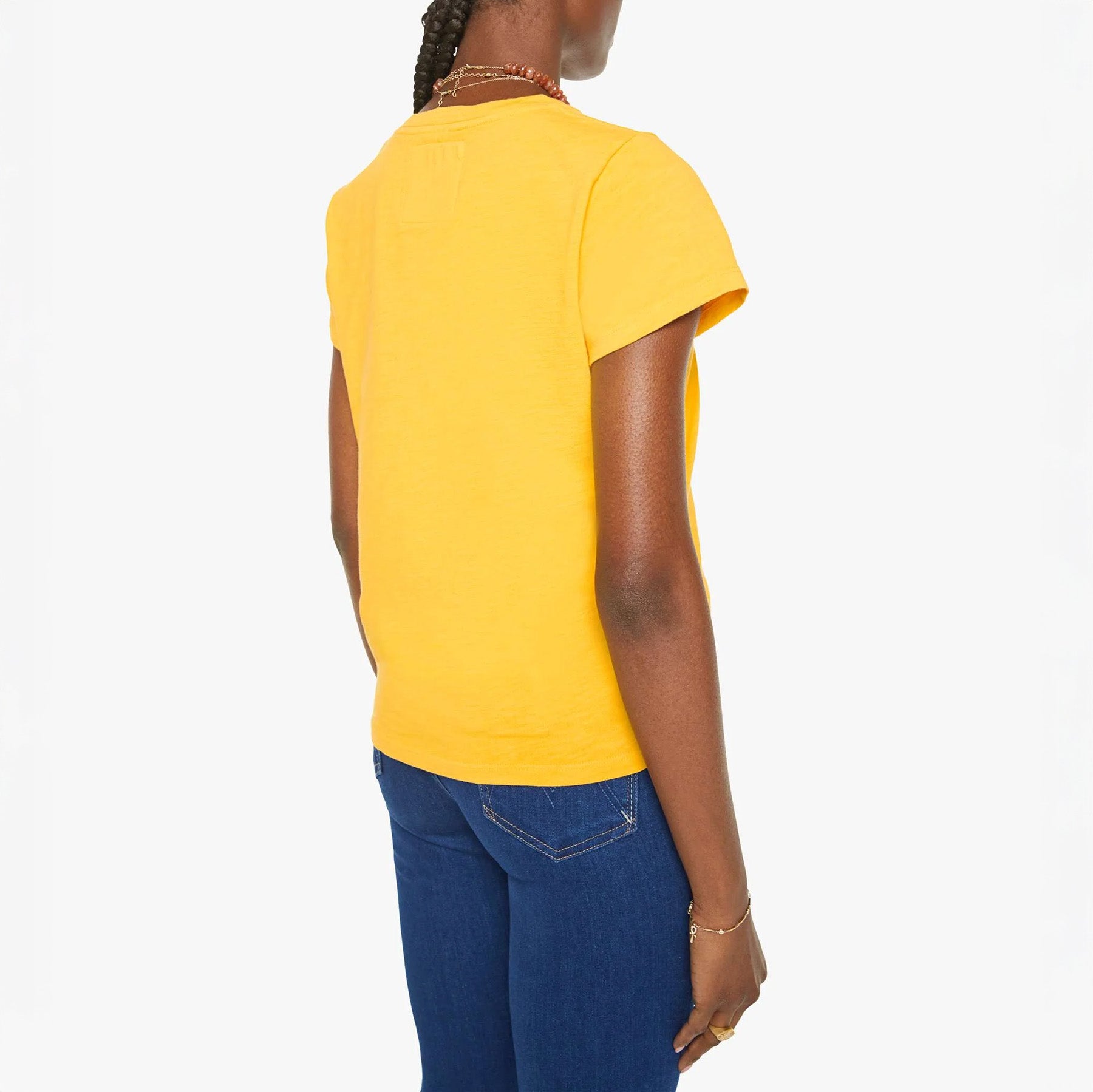 Back view of a woman wearing a yellow crewneck tee shirt paired with blue jeans.