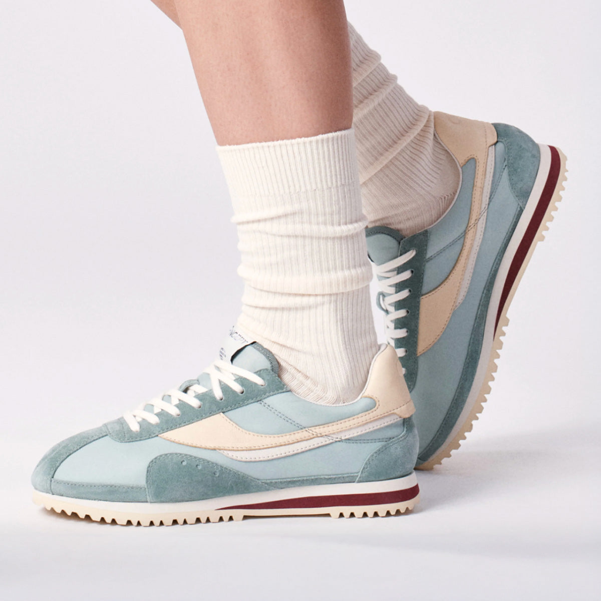 Rennes Sneaker in Agave featuring premium Italian suede upper and rubber outsole, worn with white ribbed socks.