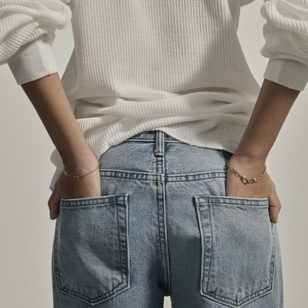 Julieta Bracelet in 9K Yellow Gold worn on wrist, showcasing decorative engraving and clasp closure against denim background.