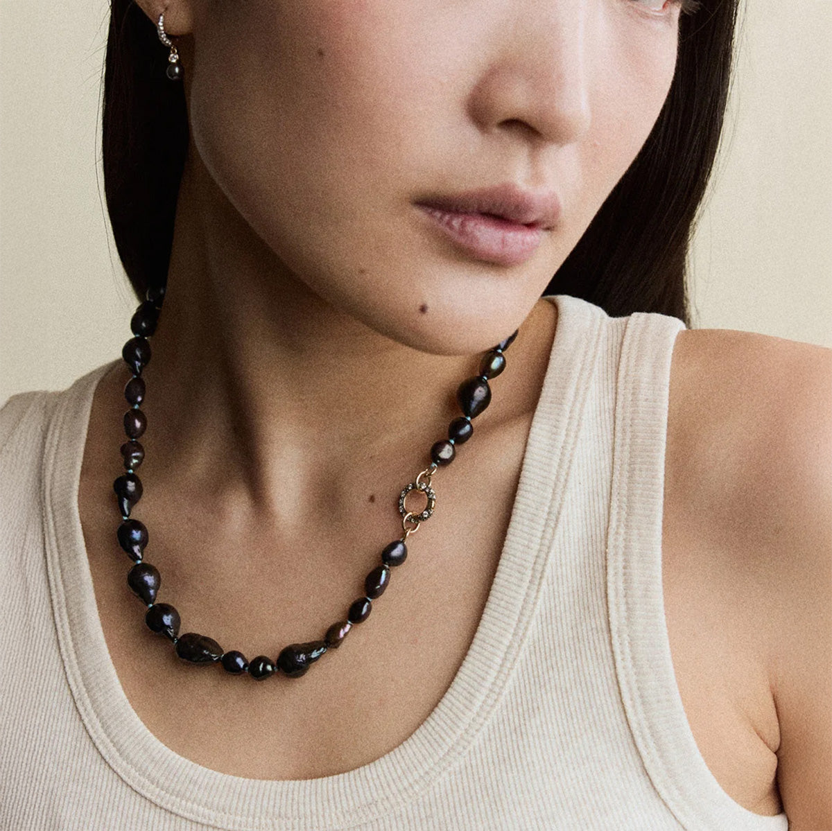 Model wearing Chaos Pearl Necklace featuring dyed black freshwater pearls and 14k gold clasp.