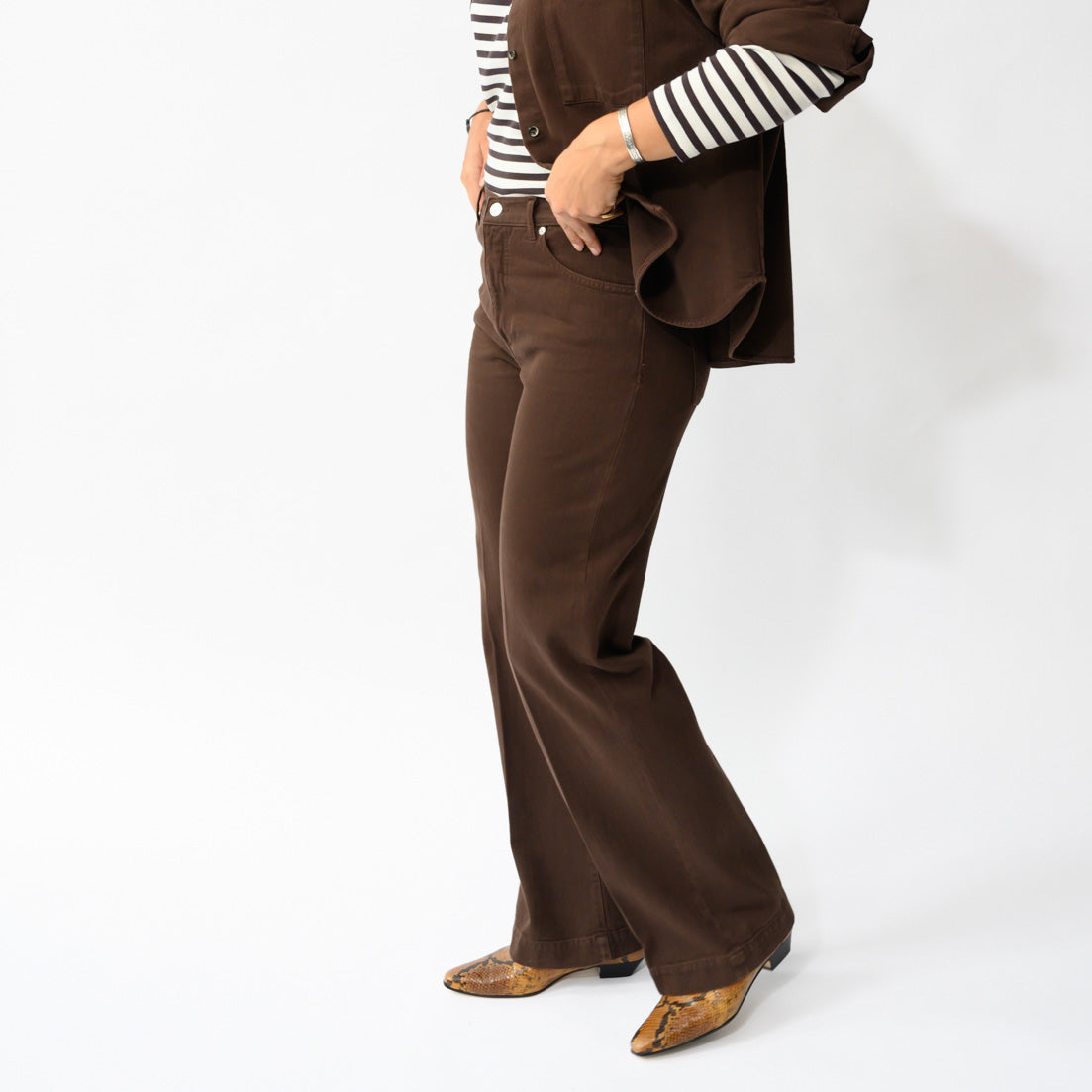Deepa Palazzo Pant in Ciocco, brown straight leg trouser shown from a side angle, paired with a striped top.