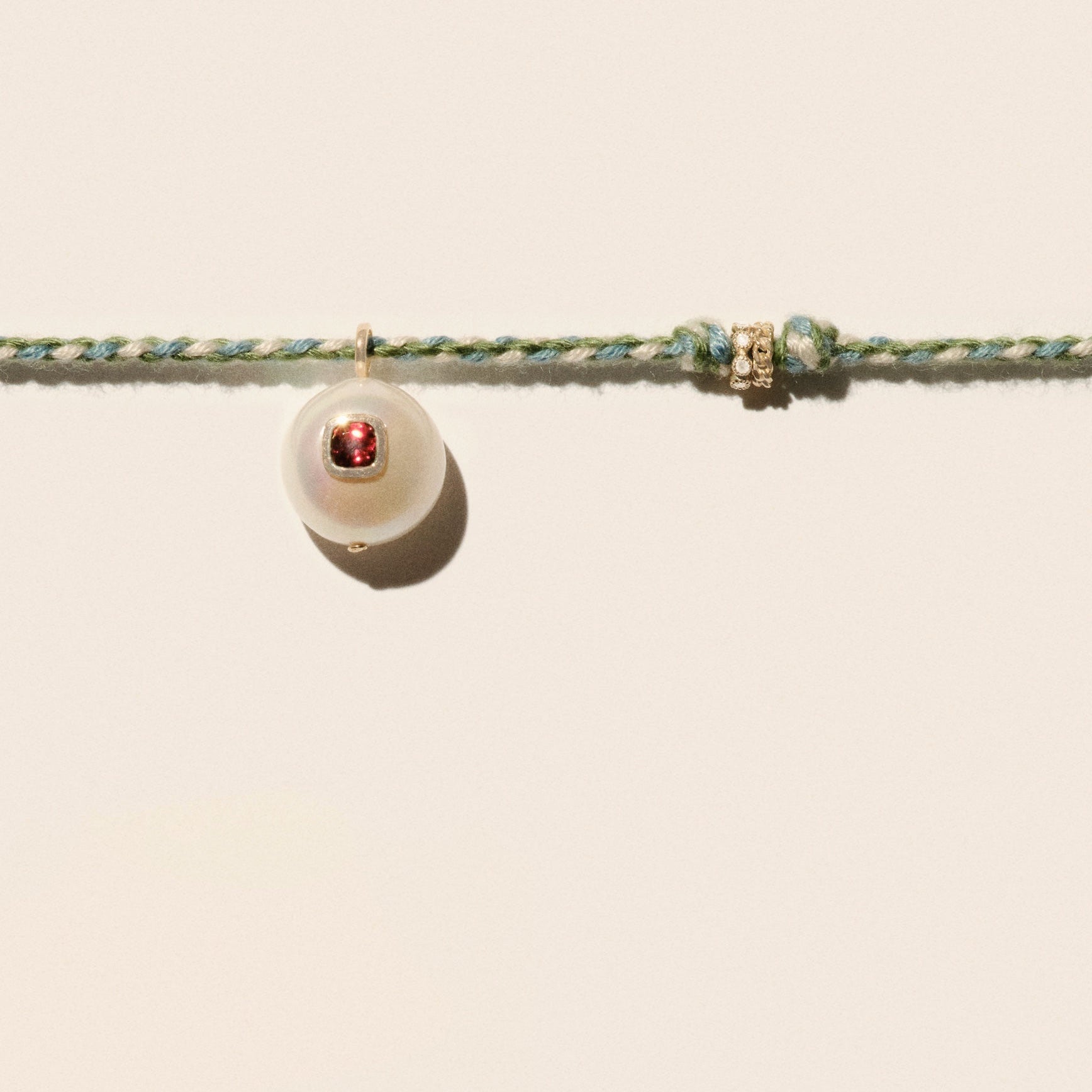 Cultured river pearl inlaid with a red garnet stone 9k yellow gold & diamond rings Mother-of-pearl button closure Length: 16" COEDDGRE