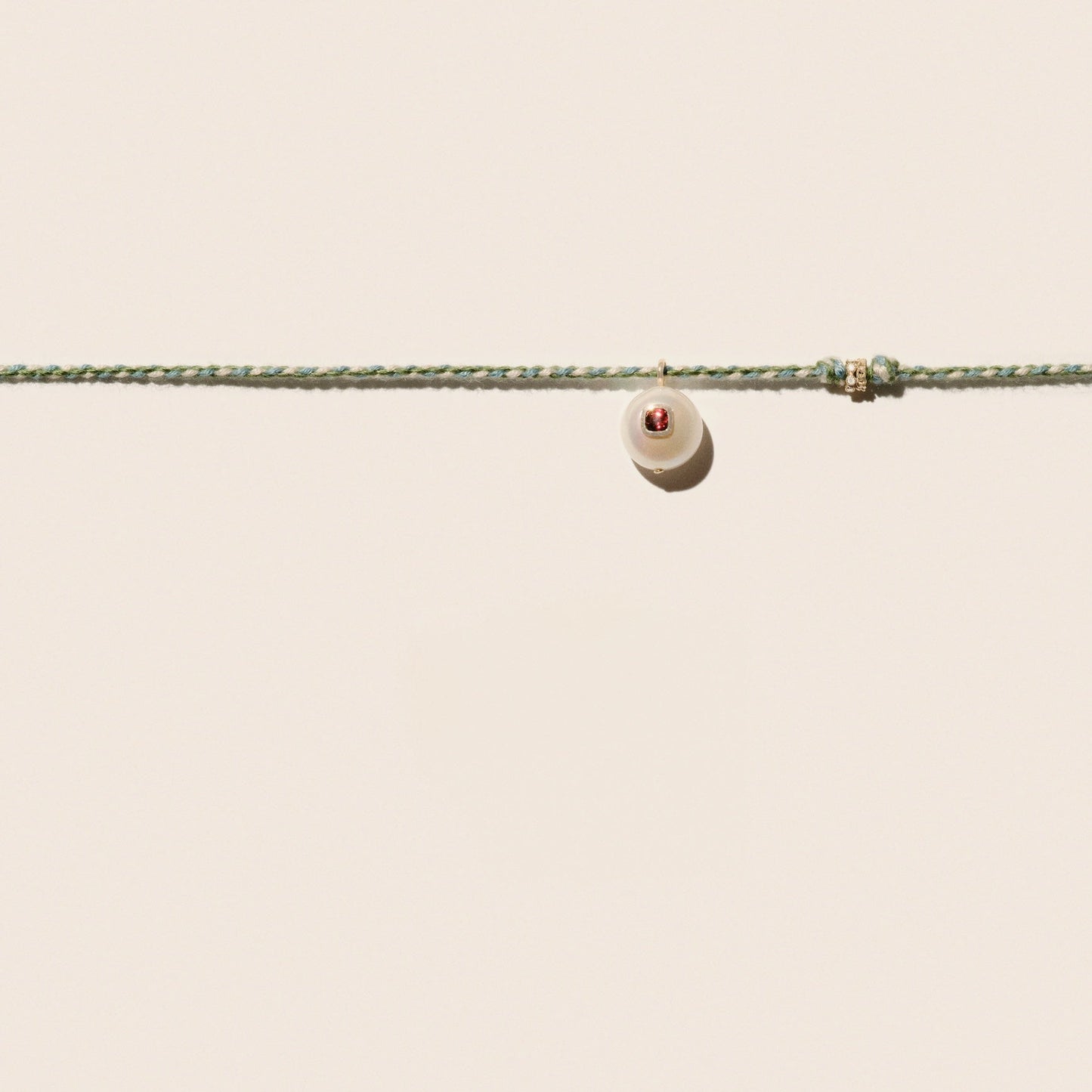 Cultured river pearl inlaid with a red garnet stone 9k yellow gold & diamond rings Mother-of-pearl button closure Length: 16" COEDDGRE