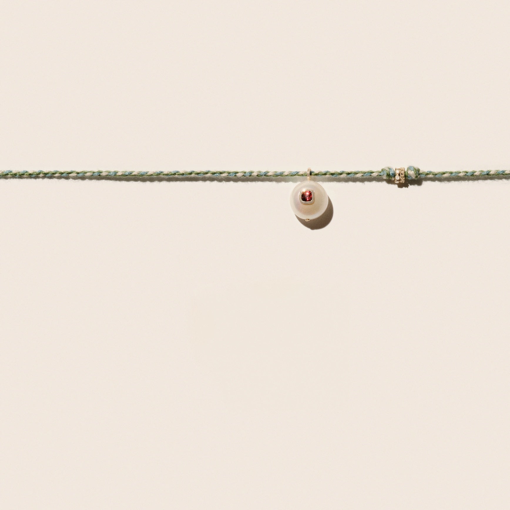 Cultured river pearl inlaid with a red garnet stone 9k yellow gold & diamond rings Mother-of-pearl button closure Length: 16" COEDDGRE