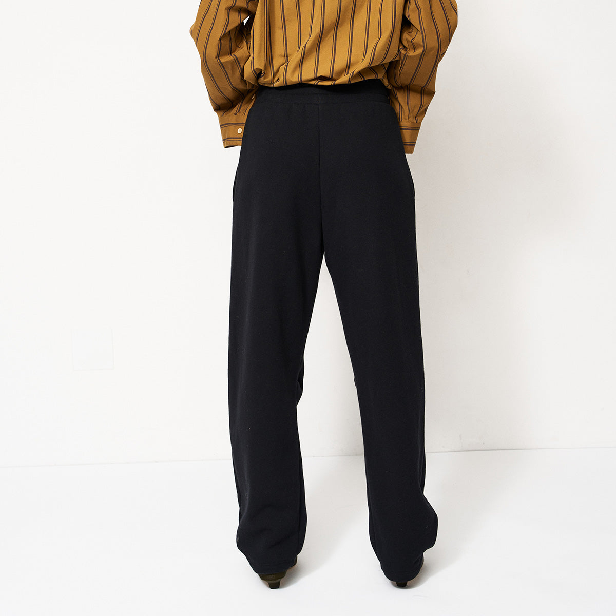 Model wearing Pintuck Track Pant in Black, showcasing the relaxed fit and pintucks at the front.