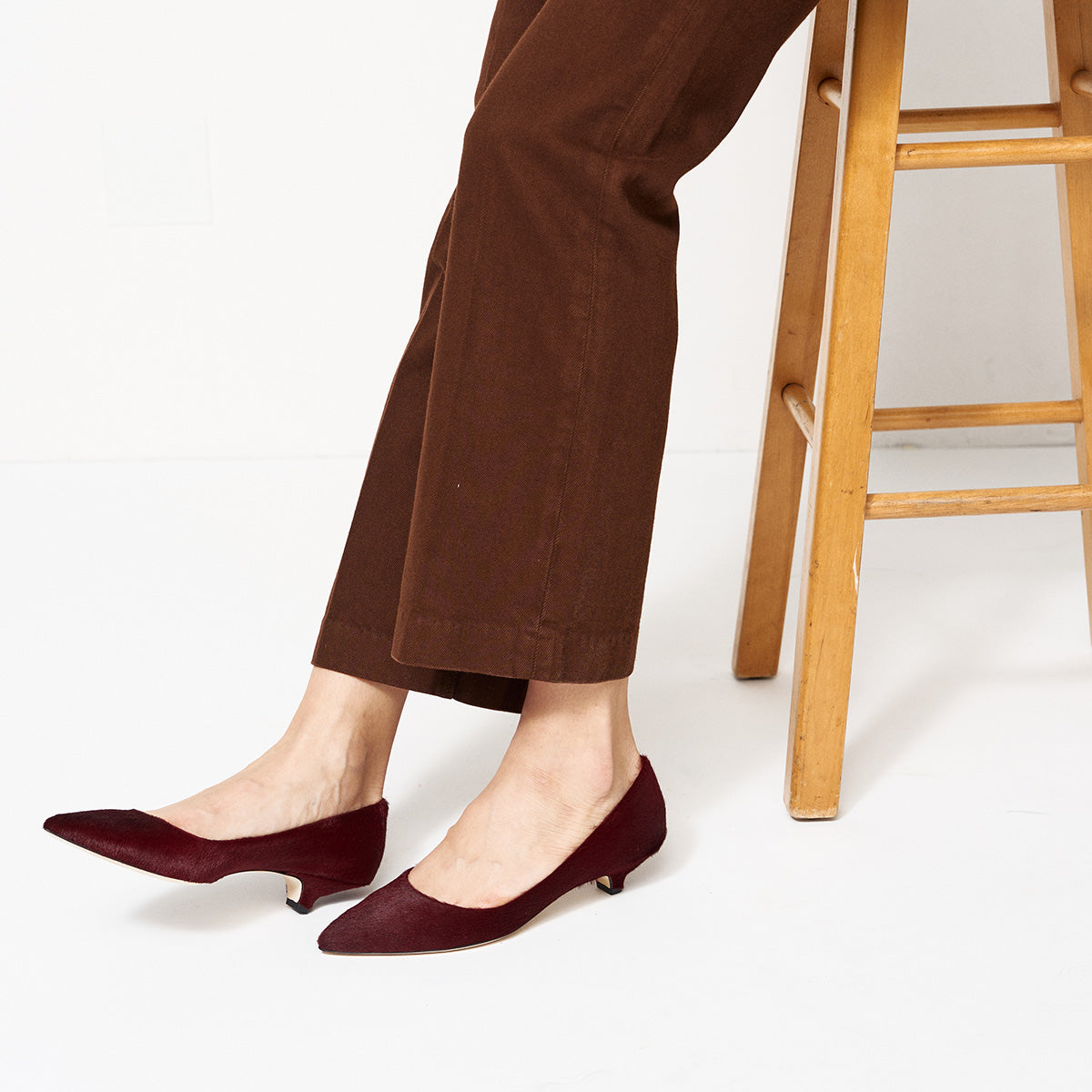 Kitty Point Heel in Claret worn with brown pants, featuring classic kitten heel design and pointed toe.