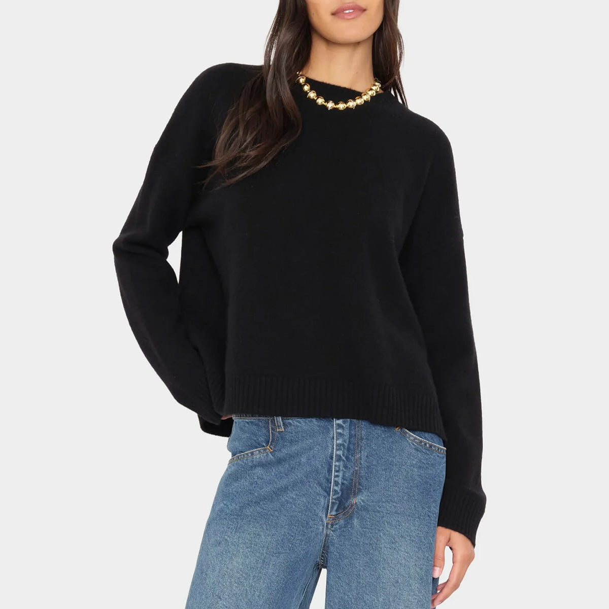 Lela Sweater in Black worn by a model, featuring drop shoulders and a ribbed hem.