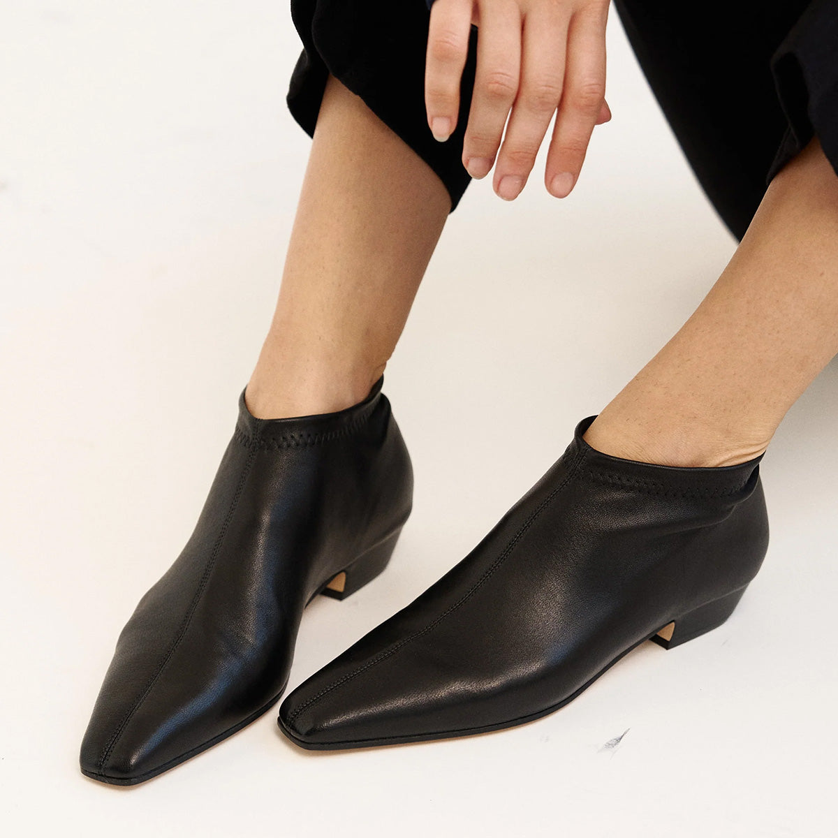 Stretch Low Boot in Black showcased on a model's feet, featuring sleek mod stretch leather and a low stacked heel.