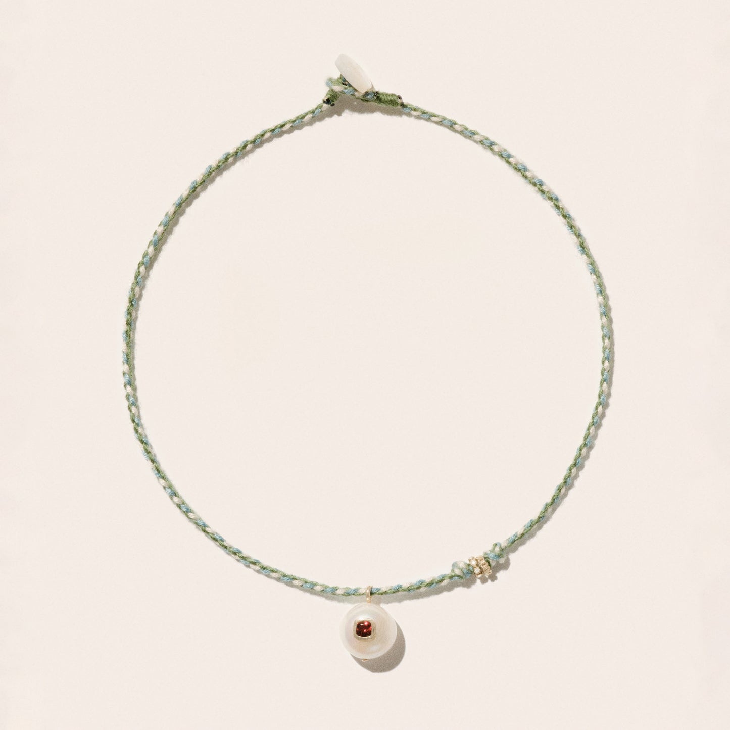 Cultured river pearl inlaid with a red garnet stone 9k yellow gold & diamond rings Mother-of-pearl button closure Length: 16" COEDDGRE