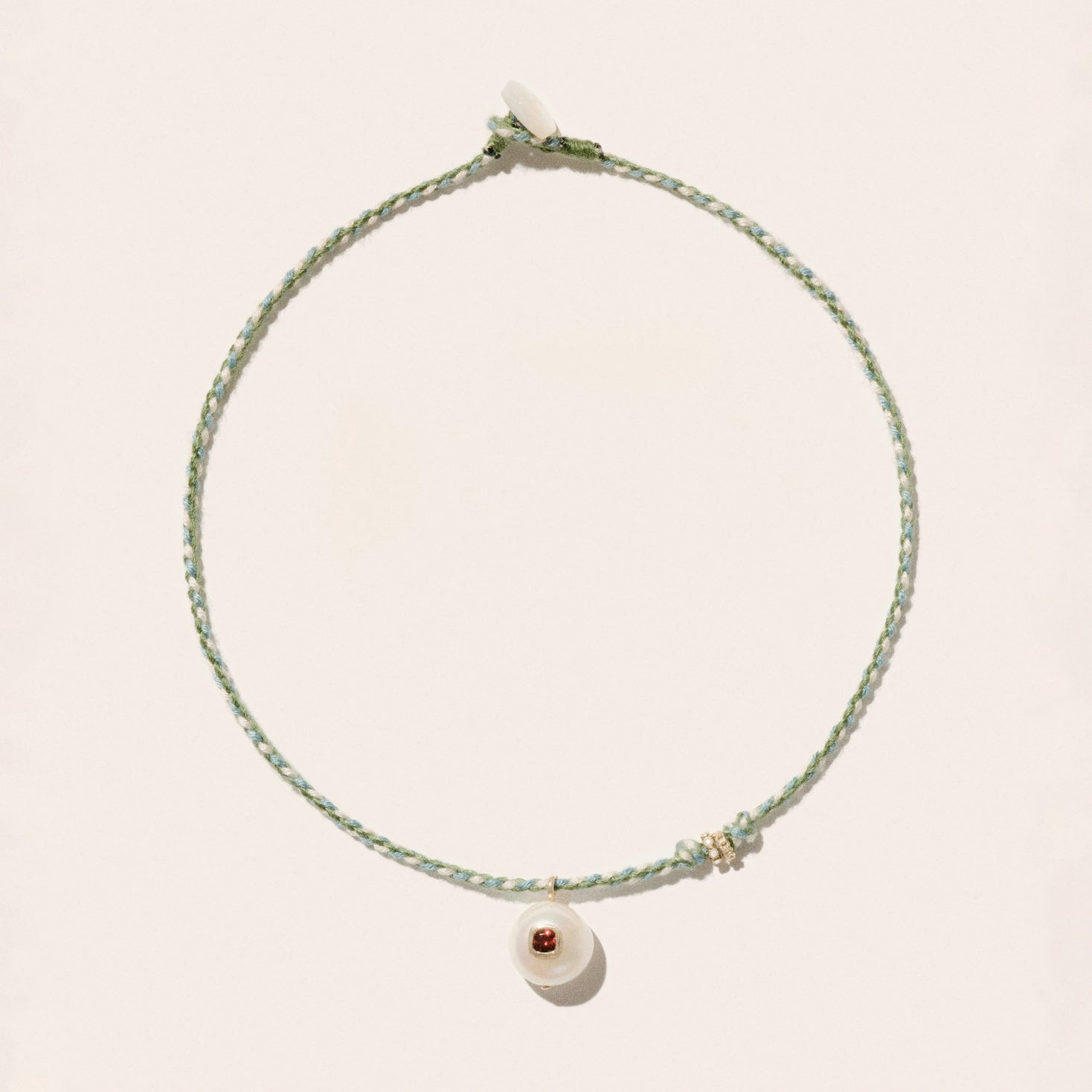 Cultured river pearl inlaid with a red garnet stone 9k yellow gold & diamond rings Mother-of-pearl button closure Length: 16" COEDDGRE